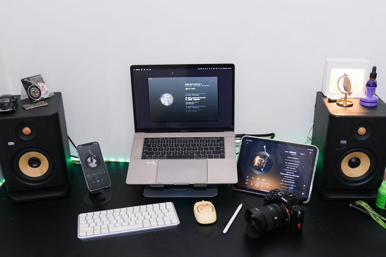 services-02 A modern home studio desk setup featuring a laptop, speakers, tablet, smartphone, and camera equipment for creative workspaces.