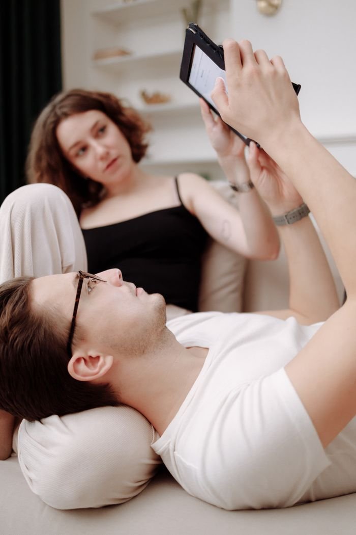 A couple enjoying leisure time indoors, browsing a tablet while relaxing together.