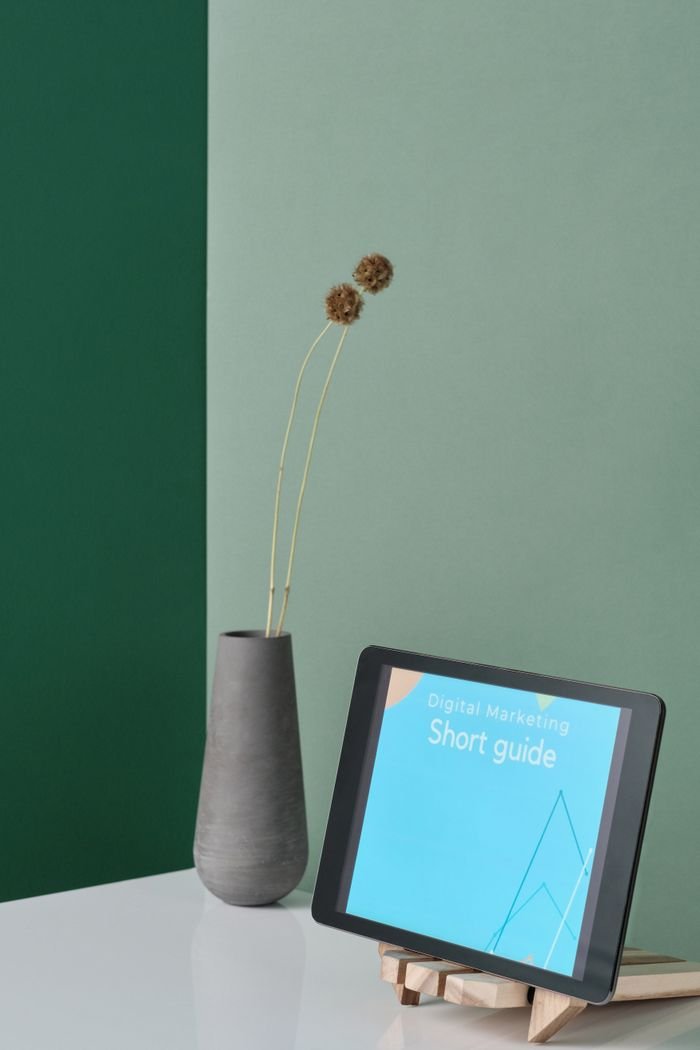 A sleek workspace featuring a tablet on a stand alongside a modern vase.